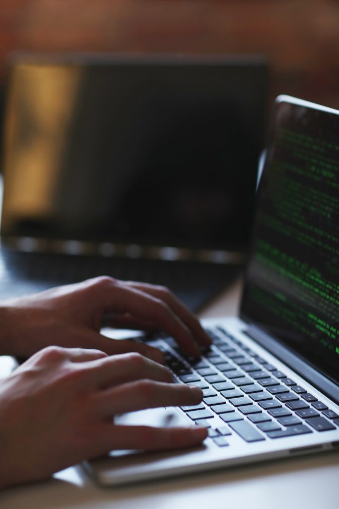 Hacker working on a laptop in a dark setting.