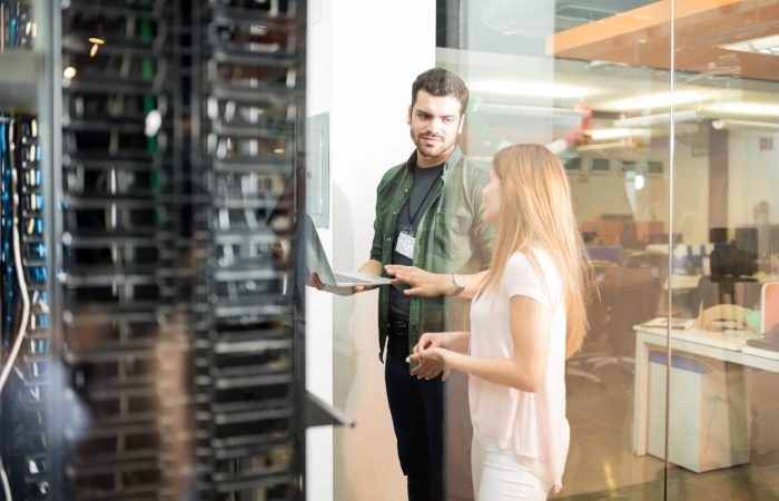 two-business-people-standing-server-room-with-laptop-discussing